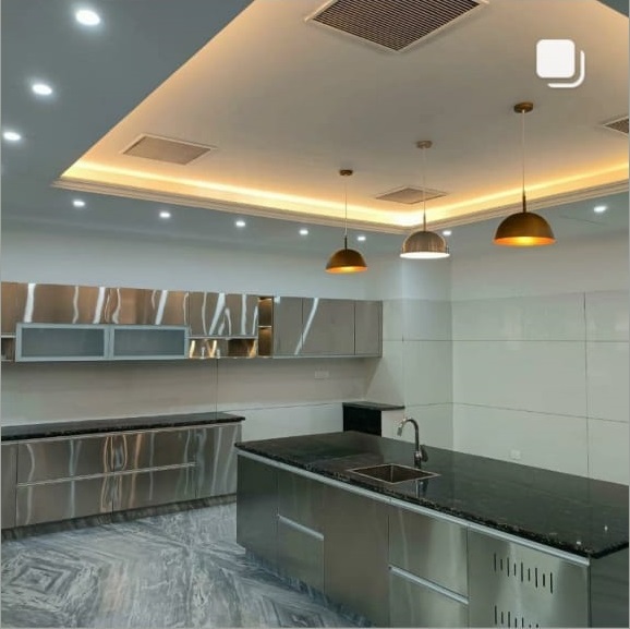 Modern kitchen with sleek stainless steel cabinetry, black granite countertops, and stylish pendant lighting. Bright and spacious design.