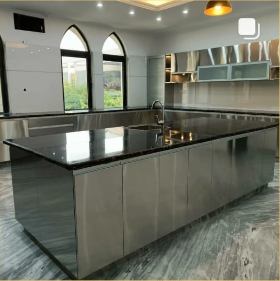 Modern kitchen featuring a large granite island, stainless steel cabinets, and large windows with arch designs, providing natural light.