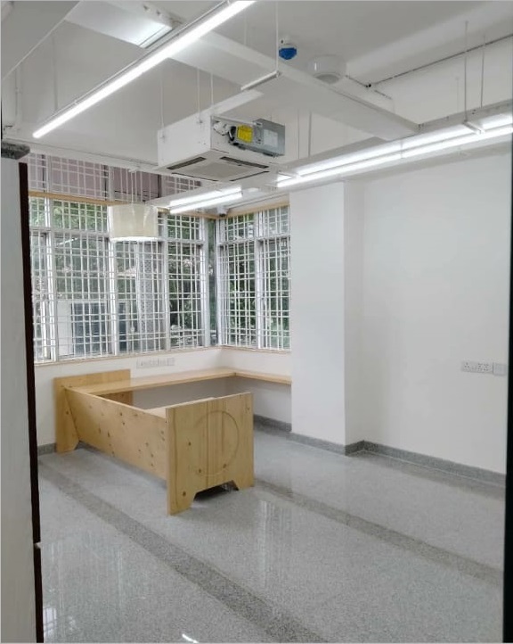 Bright, minimalistic room featuring large windows, a wooden bench, and polished gray flooring with overhead lighting.