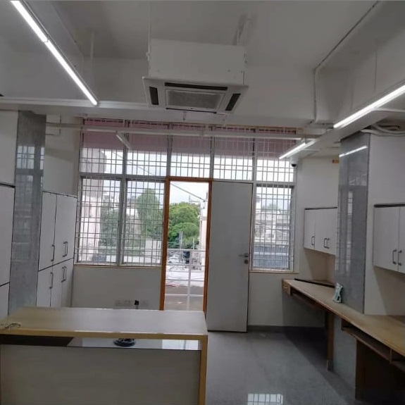 Bright, modern office space featuring a wooden desk, cabinets, and large windows allowing natural light, with a door leading outside.