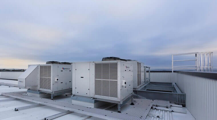 Roof-mounted HVAC units under a cloudy sky, showcasing modern cooling systems for a commercial building.